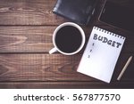 Budget planing concept. Top view of notepad with word Budget, mobile phone, cup of coffee, pouch on wooden background. Write idea success solution concept. Vintage toned picture. Copy space