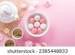 Small photo of Tang Yuan(sweet dumplings balls), a traditional cuisine for Mid-autumn, Dongzhi (winter solstice ) and Chinese new year with plum flower and tea on pastel background.