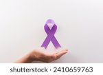 Hand holding purple ribbon on...