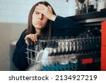 
Stressed Unhappy Woman Dealing with Dishwasher Malfunction. Unhappy lady having problems with her new appliance doing tedious chore 
