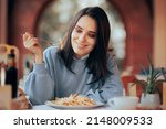 Small photo of Woman Eating French Fries with Cheese in a Restaurant. Girl eating what she wants in moderation following an intuitive eating diet