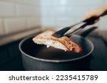 Small photo of Homemade Tuna Stake Being Flipped Over in a Pan. Person preparing a fish at home searing it on both sides