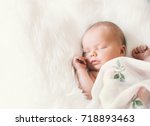 Sleeping newborn baby in a wrap on white blanket. Beautiful portrait of little child girl 7 days, one week old.