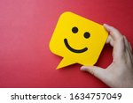 Customer service experience and business satisfaction survey. Man holding yellow speech bubble with smiley face on red background.