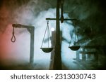 Small photo of Legal law or crime and execution concept. Death penalty miniatures on table. Man alone looking to execution at night. Artwork decoration with handcuffs, Statue of Justice and mallet of justice