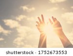 Woman hands reaches for the sky and closes the sun, the sun's rays pass through the hand