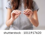 Stop smoking cigarettes concept. Portrait of beautiful smiling girl holding broken cigarette in hands. Happy female quitting smoking cigarettes. Quit bad habit, health care concept. No smoking.