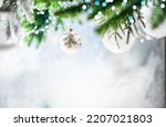 Christmas decoration with white christmas balls and fir tree branches against blurred blue background, copy space for your product or text.