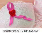 Pink ribbon with heart shaped button on white lace bra - Breast cancer concept