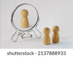 Small photo of Couple of pawns looking in the mirror with just one of them reflected in it - Concept of egoism and narcissist