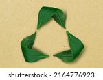 Small photo of Recycling symbol made of leaves on recycled paper background - Concept of ecology and recycling
