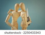 Small photo of Wooden mannequins hugging each other with knife behind back - Concept of betrayal and disloyalty