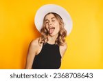 Small photo of Portrait of naughty positive woman with wavy hair in white hat standing with closed eyes and demonstrating tongue, expressing disobedience disrespect, teasing grimace studio shot, yellow background.