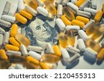 Small photo of Big pharma conspiracy theory. Medical pills lying on top of hundred of US Dollar Bill. Pharmacy and healthcare are very expensive