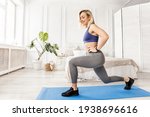 Small photo of Athletic woman in stylish sportswear doing lunges exercises at home in bedroom. Attractive blonde-hair girl standing on blue mat, working out to keep fit, healthy lifestyle concept