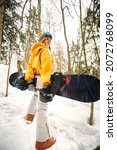 Small photo of young girl or woman snowboarder goes in for winter sports in snowy forest she stands in snow and holds a snowboard