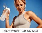 Small photo of Maintaining hydration. A woman drinks water during a workout, replenishing her water-salt balance, beautiful light, a woman quenches her thirst on a sunny day
