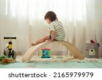 Small photo of Rear view of a female toddler playing with a balance board at a montessori playroom.