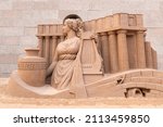 Small photo of Temporary Artwork. Sand sculpture of Terpsichore, muse of dance. The character of ancient Greek myths. A woman with her head turned to one side in a tunic and with a lyre in her hands