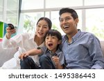 happy asian family watching tv together on sofa in living room. family and home concept