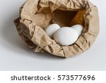 white painted easter eggs in a paper bag nest ready to be painted