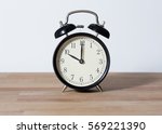 Small photo of It is ten o'clock. The time is 10:00 am or pm. A retro clock isolated on wooden table. White background. Copy space and cut.