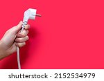 Small photo of Electric plug for a socket on a red background. The concept of electricity and its importance in everyday life. Electric plug without socket. Free space for text