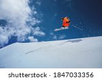 Professional athlete skier freerider in an orange suit with a backpack flies in the air after jumping on the lags on the background of blue sky and snow