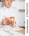 Small photo of Businessman removes wooden blocks with the word Tax. Reduction or restructuring of debt. Bankruptcy announcement. Refusal to pay loans and invalidate them.