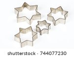 Four star shaped Christmas cookie cutters over white. Tin biscuit cutters, tool to cut cookie dough in particular shapes and to make cutouts. Hexagram shaped and six pointed geometric star figures.