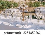 Elegant white decor for a wedding dinner at Villa Italy. The tables are decorated with white flowers in round vases. Tables without people