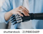 Small photo of Women with disability turns on her lightweight bionic prosthesis of arm. Female with disability using robotic hand after limb loss. Advertising of high tech artificial limbs. Medical technologies.