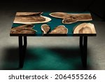 Small photo of Expensive vintage furniture. The table is covered with epoxy resin and varnished. Luxury quality wood processing. Wooden table on a concrete background. A nautical epoxy river in a rectangular slab.