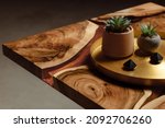 Small photo of Expensive vintage furniture. The table is covered with epoxy resin and varnished. A gold epoxy river in a round tree slab. Small cacti in concrete pots on copper spacing.