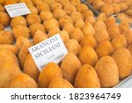 Small photo of Typical Sicilian dish arancini in the window of a local fast food. on white paper in Italian says " Sicilian arancini with meat stew and peas " street food Italy and Palermo