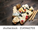 Small photo of Сheese plate gorgonzola parmesan brie or camembert and maasdam. served with berries and crackers. cheese on a wooden board
