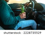 A man drinks beer while driving....