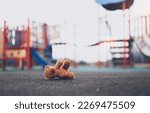 Small photo of Lost teddy bear toy lying on playground floor in gloomy day,Lonely and sad brown bear doll lied down alone in the park, Lost toy or Loneliness concept,International missing Children day