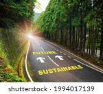Sustainable future and arrow marking on highway road and white marking lines in the forest. Inspiration and motivation concept and effort idea