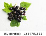 Black berries with green leaves on white texture background with copy space. Top view. Flat lay. Healthy organic blackcurrants. Food for vegetarian
