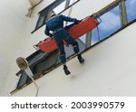 Small photo of Rescue operation. The rescuer lowers the body in a stretcher from a great height.A person is saved from high altitude. A rescuer climber evacuates a victim from a tall building.