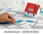 Small photo of Hand holding red pin pointing to cadastral map to decide to buy land. real estate concept with vacant land for building construction and housing subdivision for sale, rent, buy, investment