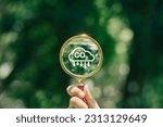 Small photo of hand holding magnifying glass with CO2 reduction icon inside.A clean and friendly environment without carbon dioxide emissions.carbon credit to limit global warming from climate change.carbon neutral.