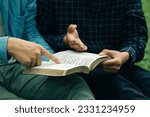 Small photo of Two men read and studied the bible at the park and prayed together. sharing the gospel with a friend. Holy Bible study reading together on Sunday.Studying the Word Of God With Friends. Education.