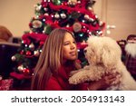 Small photo of Young cheerful woman with her puppy Meltzer for Christmas