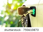 EV Car or Electric car at charging station with the power cable supply plugged in on blurred nature with soft light background. Eco-friendly alternative energy concept
