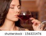 Woman drinking wine. Beautiful young woman drinking wine and keeping eyes closed 