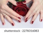 Woman's hand with red manicure and beautiful rose flower