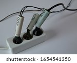 White electric extension cord with three black plugs clsoe up on white background, wires tied with banknotes of 200 and 100 Polish zloty, concept of high costs of electricty