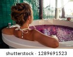 view back spa care,St. Valentine's Day. female model romantic date in jacuzzi with flowers bali eco hotel with candles.woman relaxed in a bath with tropical petals.International Women's Day March 8